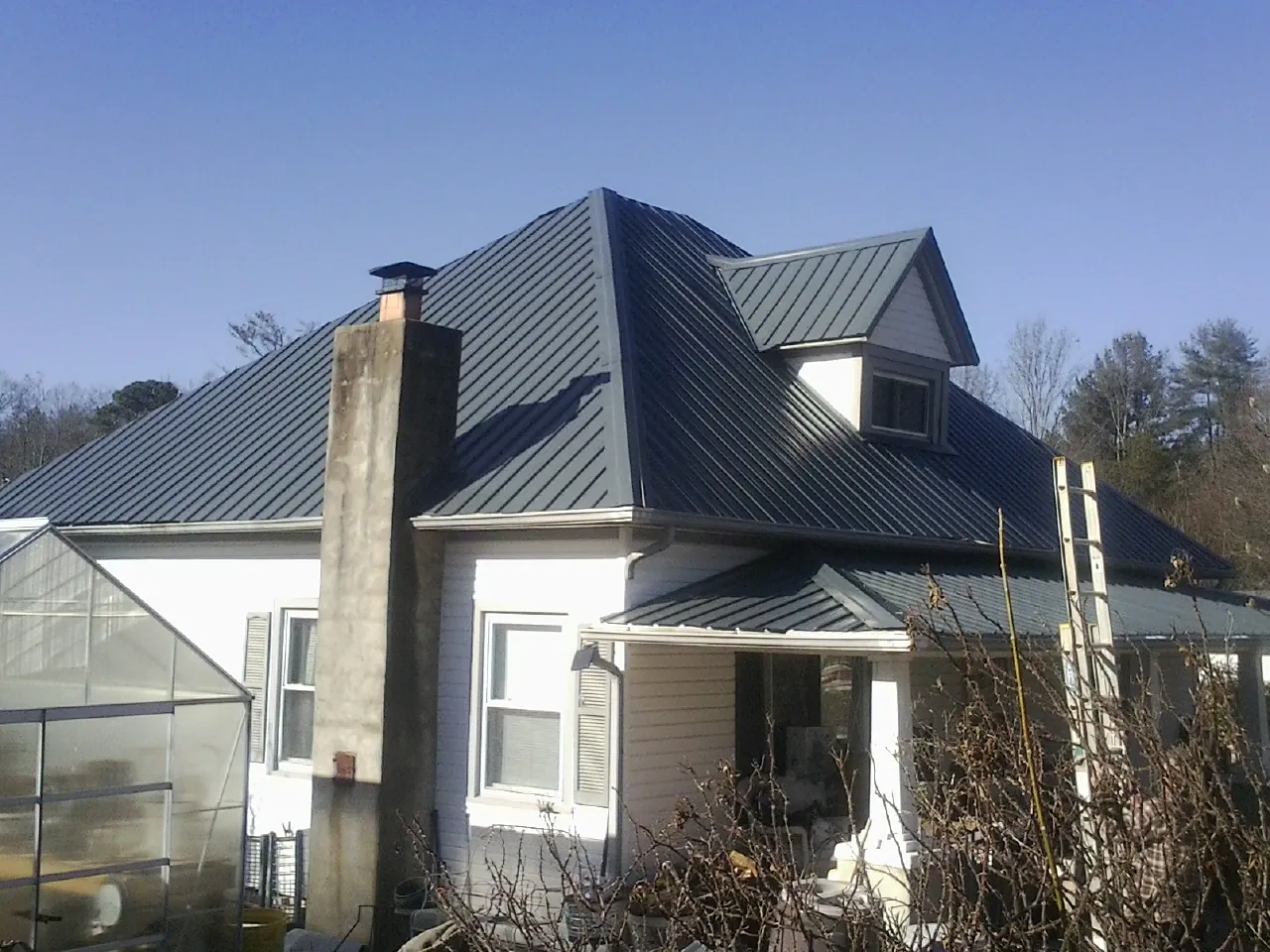 Dark blue standing seam metal roof on a white farmhouse with dormer — Slate & Tile Roof Repair by Roofing Brothers in Newburyport