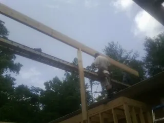 Carpenter setting a ridge beam over a new addition frame — Ice Dam Removal by Roofing Brothers in Newburyport