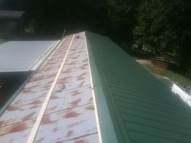 Old rusted panels beside newly installed green metal roofing — Wind Damage Roof Repair by Roofing Brothers in Newburyport