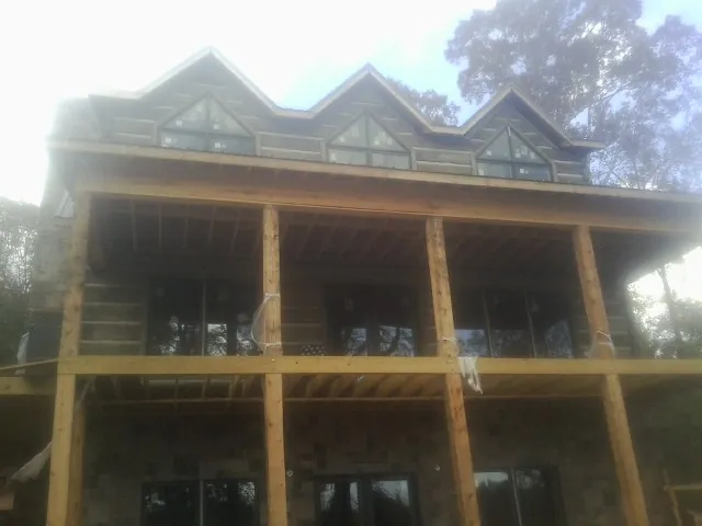 Dormers and porch framing on a large log home under construction — Roof Coating work by our crew in Newburyport