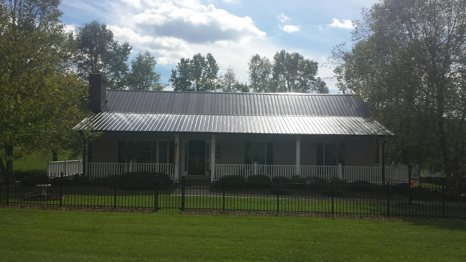 Gray metal roof on a brick ranch with a full width front porch — Gutter Guard Installation work by our crew in Newburyport
