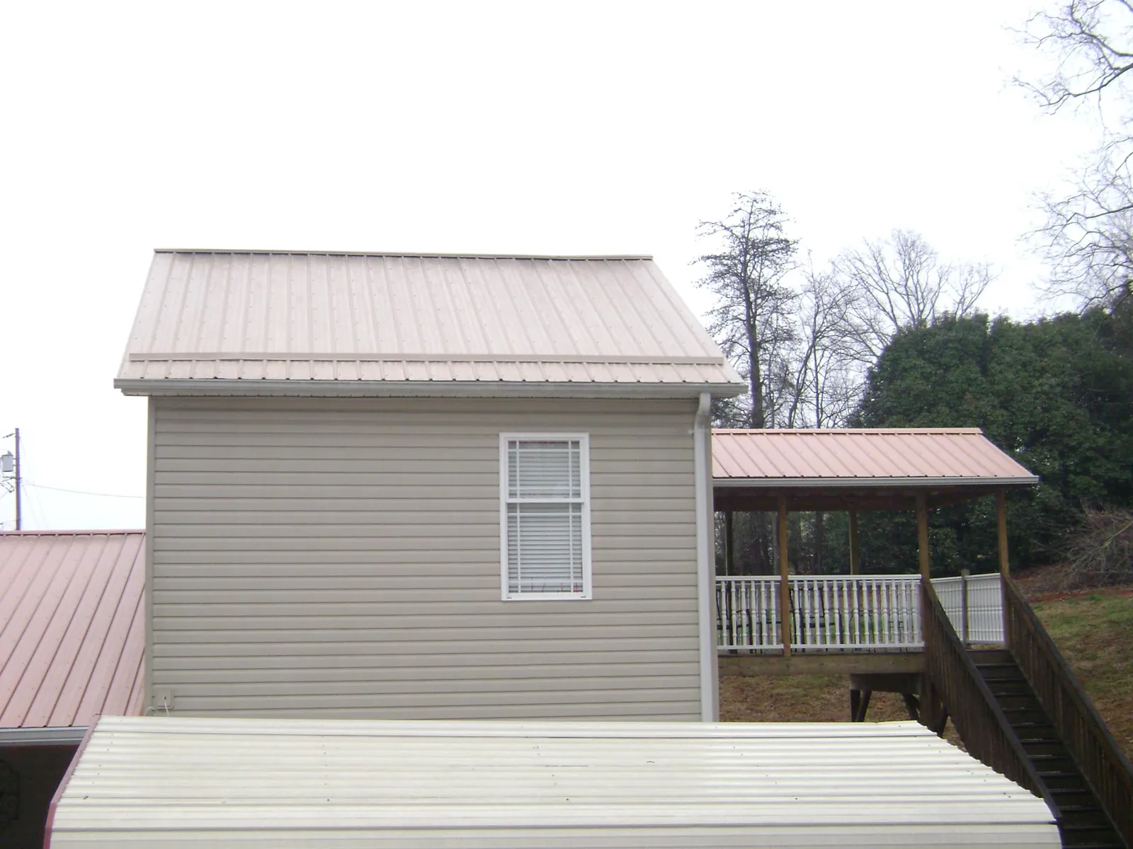 Tan metal roofs on a two story addition and attached porch, from a Roof Replacement job in Newburyport