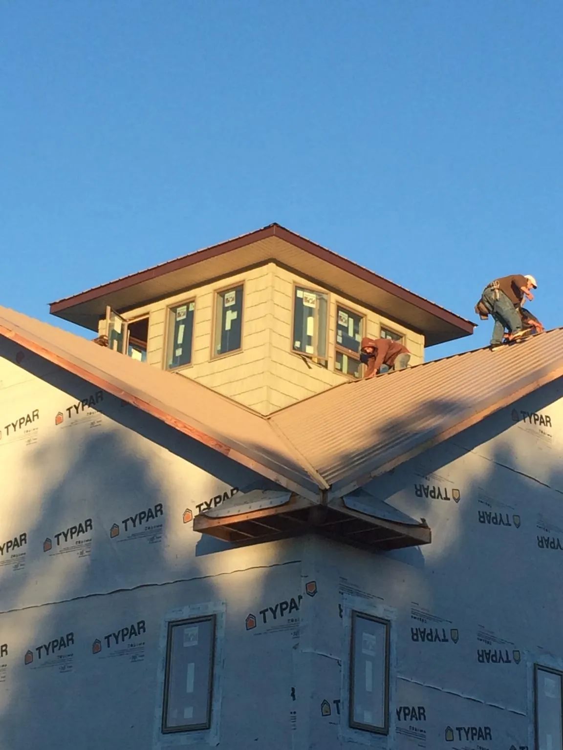 Roofers working around a rooftop cupola on a new metal roof at sunset — Roof Waterproofing in Newburyport by Roofing Brothers